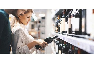 Woman and man reading wine bottle at grocery store